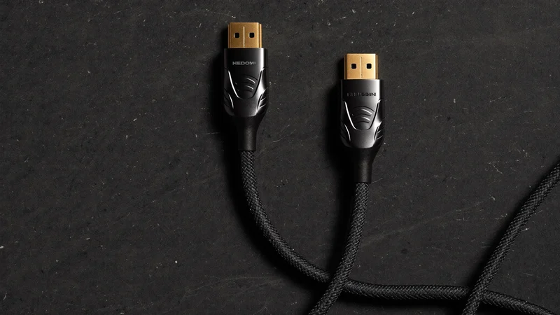 Cablu HDMI așezat curbat pe ardezie, cu ambii conectori vizibili